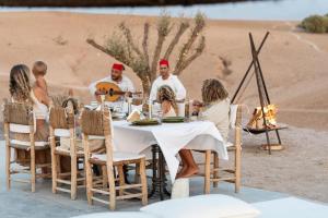 a group of people sitting around a table in the desert at Emeraude Camp Agafay in El Karia