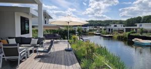 a patio with an umbrella next to a river at Harderwold Villa - 384 in Zeewolde