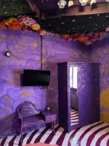 Ein Zimmer mit einer lila Wand, einem Fernseher und einem Stuhl in der Unterkunft Paciu Maison - Dimora Artistica Immersiva in Ozzano dell’Emilia