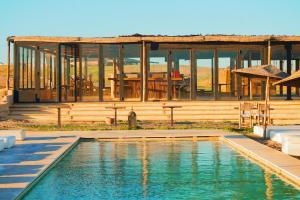 a house with a swimming pool in front of a building at Emeraude Camp Agafay in El Karia