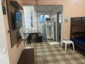 a small room with a bed and a desk with a television at Kitnet Cantinho 26 in Mongaguá