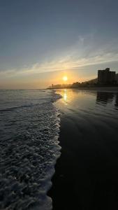 a sunset on a beach with the tide coming in at Kitnet Cantinho 26 in Mongaguá +5 photos