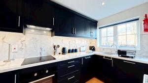 a kitchen with black cabinets and a sink and a window at Baileys Beach House - Part of the The Bay Filey Holiday Village with pool, gym and direct beach access, pub, restaurant, tennis and meadows walks in Filey +37 photos