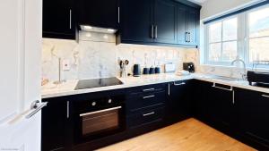 a kitchen with black cabinets and a sink and a window at Baileys Beach House - Part of the The Bay Filey Holiday Village with pool, gym and direct beach access, pub, restaurant, tennis and meadows walks in Filey
