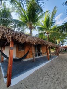 a resort with a hammock and two palm trees at ArpoadorBangalôparaísoperdido in Tutóia
