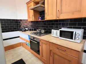 a kitchen with a microwave and a stove at Cozy corner - 3 Bedroom Full House - Perfect for Families, Couples And Company Contractors in Wakefield +15 photos
