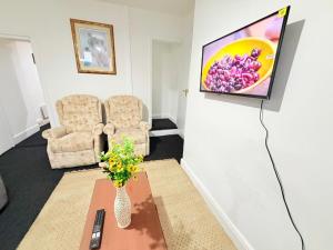 a living room with a chair and a vase of flowers at Cozy corner - 3 Bedroom Full House - Perfect for Families, Couples And Company Contractors in Wakefield