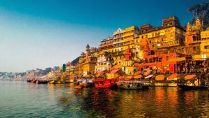 a group of buildings next to a river with boats at Jogi Lodge in Varanasi
