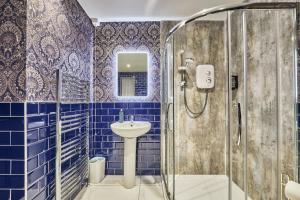 a blue tiled bathroom with a sink and a shower at Jazz House in Derry Londonderry