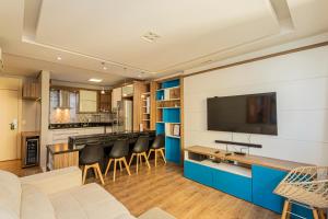 a living room with a couch and a tv on a wall at SEQ - Sequoia Alphaville By Anora Spaces in Barueri