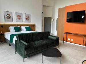 a bedroom with a bed and a green leather couch at Heritage X in São Paulo