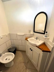 a bathroom with a sink and a toilet and a mirror at Departamento Céntrico 3 in El Bolsón