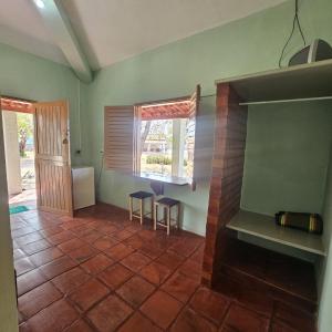 a living room with a fireplace and two stools at Pousada Mae Natureza Icapuí in Icapuí