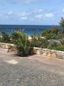 a cobblestone road next to a stone wall and the ocean at Casa Silvina Tarrafal in Tarrafal