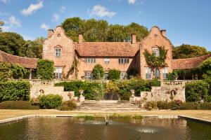 an old house with a pond in front of it at Port Lympne Mansion Hotel in Hythe