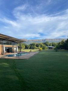 a building with a large field with mountains in the background at Hartbeespoort Escape Hot Tub and Mountain Views in Skeerpoort
