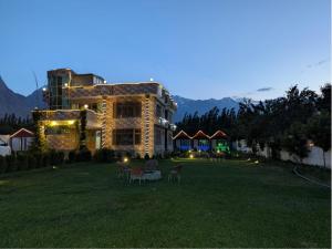a large building with chairs in a yard at night at Comfort Hotel & Huts in Skardu