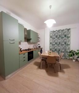 a kitchen with green cabinets and a table with chairs at Blossom House in Isola delle Femmine