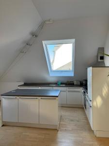 a kitchen with white cabinets and a window at Helle Dachgeschoßwohnung am Laurentiusplatz in Wuppertal +7 photos
