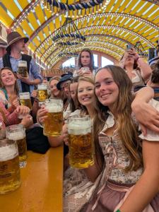 a group of people holding upints of beer at Beer Base-Camp 'BASIC PACKAGE' Oktoberfest Camping, with free welcome beer and traditional lederhosen-dirndl shop in Munich