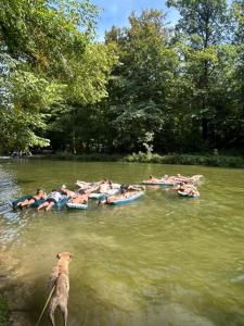 a group of people in boats on a river with a dog at Beer Base-Camp 'BASIC PACKAGE' Oktoberfest Camping, with free welcome beer and traditional lederhosen-dirndl shop in Munich
