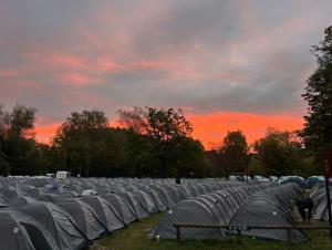 a group of tents in a field with a sunset at Beer Base-Camp 'BASIC PACKAGE' Oktoberfest Camping, with free welcome beer and traditional lederhosen-dirndl shop in Munich