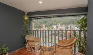 a balcony with chairs and a view of a city at Hotel Ishan - A Ganges Riverside Retreat by Salvus in Rishīkesh