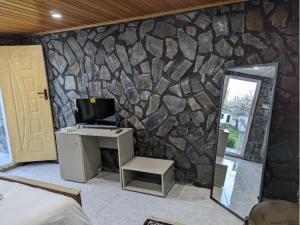 a room with a stone wall with a desk and a computer at Comfort Hotel & Huts in Skardu