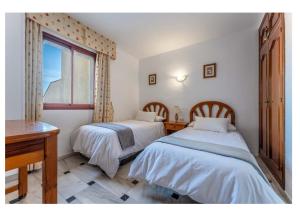 two beds in a room with a desk and a window at Urb. Lubina Sol in Mijas Costa +20 photos