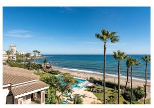 a view of a beach with palm trees and the ocean at Urb. Lubina Sol in Mijas Costa