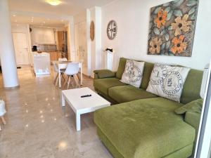 a living room with a green couch and a table at La Cala de Mijas, groundfloor 2 bed apartment steps away from the beach in Mijas Costa