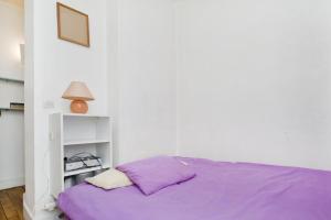 a bed with purple sheets in a white room at CHAMPS ELYSEES STUDENT STUDIo in Rosières-près-Troyes
