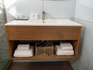 a bathroom vanity with a sink and towels at TStays Smart Hotel Courtyard, Gated Modern Stay in Port-of-Spain