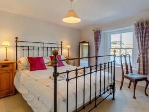 a bedroom with a bed and a chair and a window at 2 Bed in Polruan oc-pc033 in Fowey