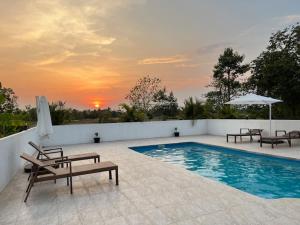 a swimming pool with two benches and an umbrella at Ranch Seda Mosegaard in Amphoe Khukhan