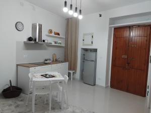 a white kitchen with a table and a refrigerator at Lucy Home in Pisticci
