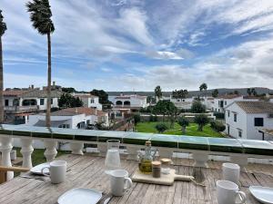 a table on a balcony with a view of a city at Apartamento con piscina SS20 in Fornells +20 photos