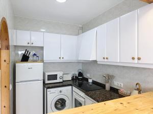 a kitchen with white cabinets and a washer and dryer at Apartamento con piscina SS20 in Fornells