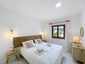 a bedroom with a large bed with white sheets at Apartamento con piscina SS20 in Fornells