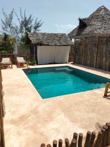 a pool in a resort with a thatch roof at Sunset Lover in Michamvi
