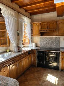 a kitchen with wooden cabinets and a black stove at Casa Conchas in Ferreira