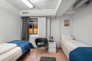 a bedroom with two beds and a chair in it at Tromso Downtown Apartments - Main Street in Tromsø