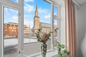 a vase with flowers in a window with a church at Tromso Downtown Apartments - Main Street in Tromsø