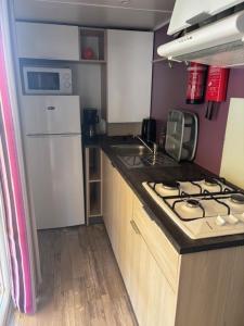 a small kitchen with a stove and a refrigerator at Le Cocon Landais in Capbreton
