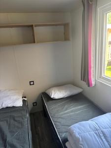 two beds in a small room with a window at Le Cocon Landais in Capbreton
