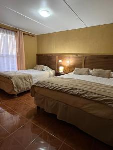 a hotel room with two beds and a window at Hostal Piedrita de Rio in San Pedro de Atacama
