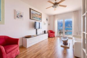 a living room with a television and a red chair at Mont&Lac Lake View Apartment in Limone in Limone sul Garda