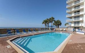 a swimming pool next to a building with chairs and the ocean at SeaSpray West 303-Gulf Front in Perdido Key