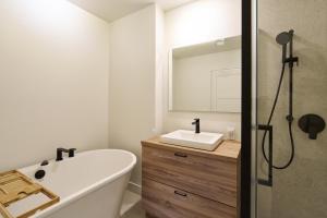 a bathroom with a bath tub and a sink at Unité 104 in Beaupré