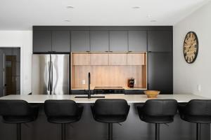 a kitchen with black cabinets and a counter with black chairs at Unité 104 in Beaupré +9 photos